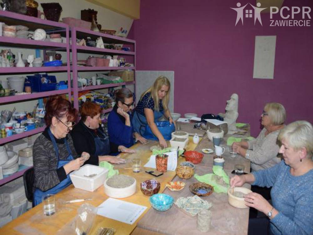 Zdjęcie: Grupa kobiet wypełnia formy przy dużym stole w pracowni ceramicznej
